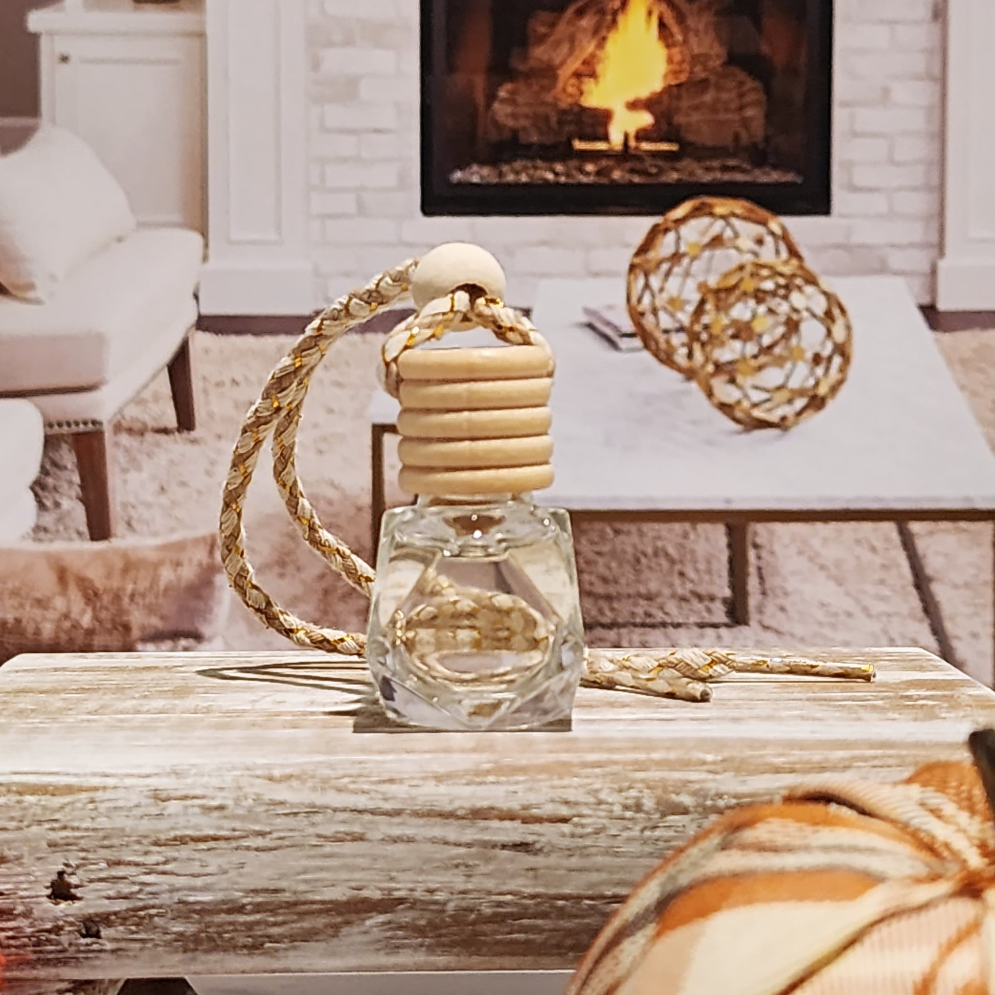 A car diffuser bottle with a wooden lid and a rope attached, displayed on a wooden surface with a cozy background.